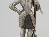 figurine of a man in armor with a sword on a wooden base