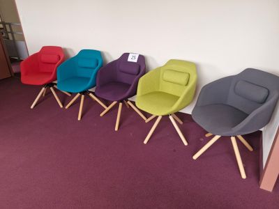 plusieurs chaises de différentes couleurs alignées contre un mur dans une pièce