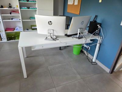 un bureau blanc sur lequel sont posés deux ordinateurs, dans une pièce