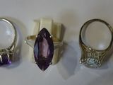 three rings with amethorate and diamonds on a white surface