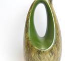 a green vase that is sitting on a white surface