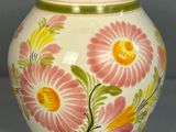 un vase blanc orné de fleurs roses et jaunes peintes dessus