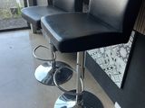 two black leather bar stools in front of a window