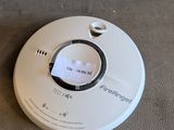 a white smoke detector on the floor next to a remote control