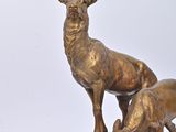 bronze statue of two deers on a rock with a white background
