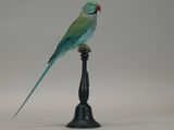 a green bird sitting on top of a black stand
