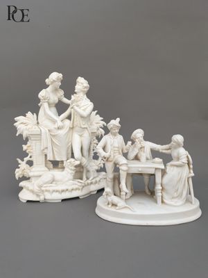 two white figurines of people sitting at a table