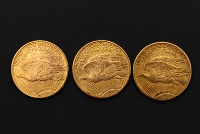 trois pièces d'or représentant des têtes d'aigle sur fond noir