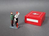 a small figurine of a man and woman standing next to a red box