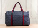 un sac de voyage bleu et rouge posé sur une table en bois
