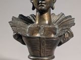 bronze bust of a woman holding a book on a pedestal