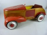 Une petite voiture ancienne est posée sur une surface blanche.