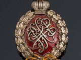 a close up of a gold and red broochle on a black surface
