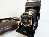 an old camera and a brown bag on a table