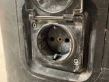 a close up of a parking meter with an electrical outlet