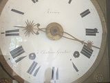 clock with roman numerals on the face of it in a glass case