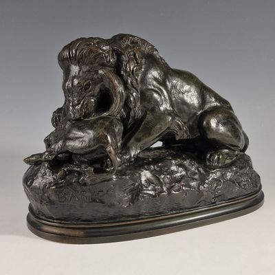 statue en bronze représentant un lion perché sur un rocher, tenant une souris dans la gueule