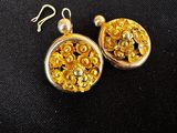 boucles d'oreilles plaquées or ornées de perles dorées sur fond noir