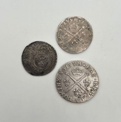trois pièces d'argent posées l'une à côté de l'autre sur une surface blanche