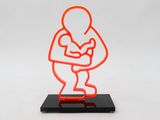 an orange neon sculpture of a man holding a baby on a black base