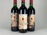 three bottles of red wine sitting on top of a white table