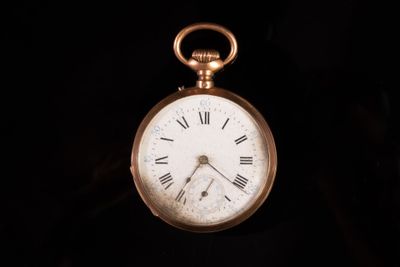 une montre de poche en or avec des chiffres romains sur le cadran