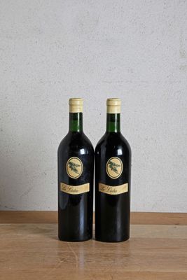 two bottles of wine sitting on a table next to each other