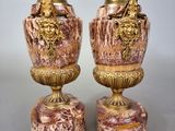pair of antique vases on marble bases on a gray surface