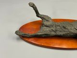 a sculpture of a cat laying on top of a wooden plate