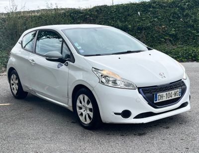 a white car parked in a parking lot next to a hedge