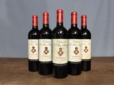 four bottles of red wine are lined up on a wooden table