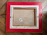 an old picture frame with a blue button in it sitting on a wooden floor