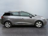 the silver car is parked in the parking lot near the wall