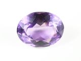un gros plan d'une pierre d'améthorate violette posée sur une surface blanche