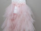 pink tulle dress hanging on a hanger against a white wall