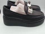 pair of black loafers with white fur lining and buckles on top of a box