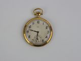 une montre de poche en or sur une surface blanche