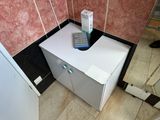 a white box with a remote on top of it in the corner of a bathroom