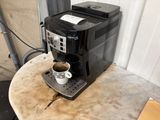 a coffee maker sitting on a table with a cup of coffee