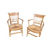 two wooden chairs sitting next to each other on top of a white surface