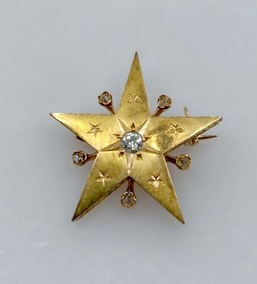 un gros plan sur une broche en forme d'étoile en or sertie de diamants