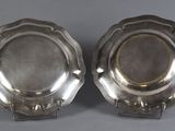 a pair of silverplated dishes on stands on a grey background