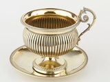 une tasse et une soucoupe anciennes en argent, avec une soucoupe posée sur une autre soucoupe