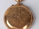 a small gold pocket watch on a white surface