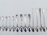 six silver spoons are lined up in a row on a white surface