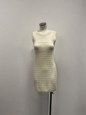 a white dress on a mannequin stand against a white wall