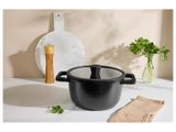 La casserole noire est posée sur le plan de travail, à côté d'une planche à découper.