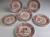 six assiettes rouges et blanches sur lesquelles figurent les portraits d'un homme et d'une femme