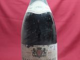 an old bottle of wine sitting on top of a red table