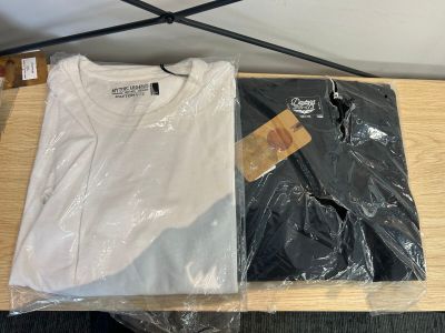 une chemise blanche et une chemise noire posées sur une table